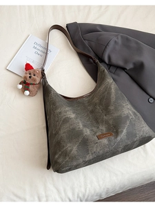 Flat lay of vintage grey tote bag with brown leather trim and a cute plush bear charm