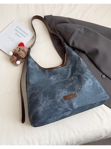 Detail of the blue denim tote bag texture with brown leather piping and decorative charms
