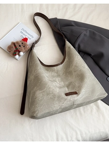 Macro detail of vintage textured gray-green hobo bag with brown leather trim and metal logo