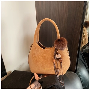 Détail d'un sac seau en daim fauve avec logo doré et pendentif en fourrure douce