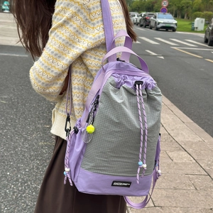 Dettaglio dello zaino patchwork viola e grigio con ciondolo a forma di pallina da tennis