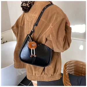 Modische schwarze Beuteltasche am Model mit einem orangefarbenen Monster-Anhänger