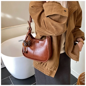 Detailaufnahme der braunen Retro-Schultertasche mit Leopardenmuster-Bommelanhänger