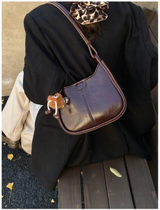Detail der braunen Vintage-Eimertasche aus Leder mit niedlichem Plüschmonster-Anhänger