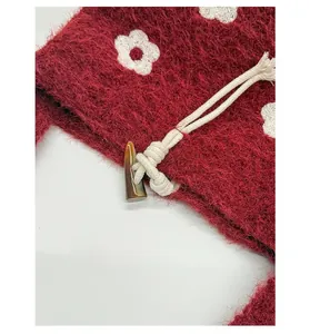 Détail macro du sac seau en tricot rouge avec motif floral blanc et bouton en corne