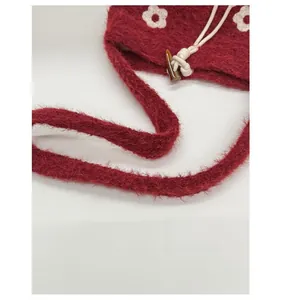 Détail du sac seau en peluche bordeaux avec motifs floraux blancs et fermeture bouton bois