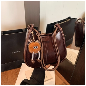 Detailansicht der dunkelbraunen Hobo-Tasche aus Ölwachsleder mit süßem Plüsch-Anhänger