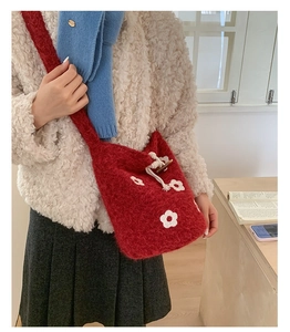 Détail du sac seau en peluche rouge avec motif floral et fermeture à bouton en bois
