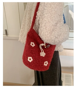 Détail du sac seau en peluche rouge avec fleurs blanches et cordon de serrage crème