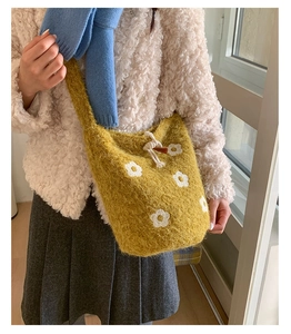 Détail du sac seau en tricot jaune avec motifs floraux blancs et fermeture à cordon
