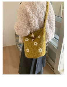 Détail d'un sac seau jaune en peluche avec fleurs tricotées et cordon de serrage