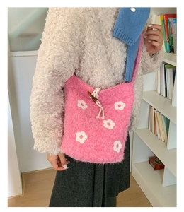 Gros plan du sac seau en maille rose pelucheuse avec motifs fleurs et bouton bascule