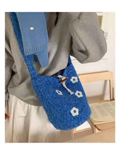 Détail du sac seau en polaire bleue avec broderies de fleurs blanches et fermoir bûche