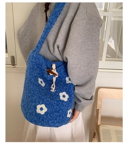 Détail du sac seau en peluche bleue avec motif floral blanc et cordon à bouton en bois