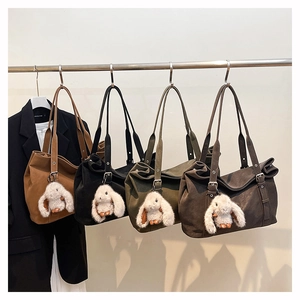 Detail of vintage matte tote bag showing plush bunny charm and silver buckle straps