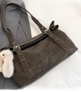 Detail of matte charcoal tote bag with twin buckle straps and white plush chicken charm