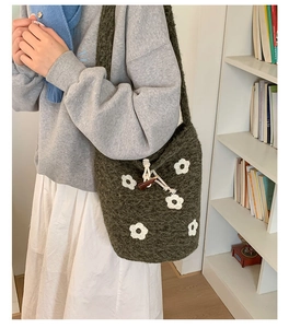 Vue détaillée du sac seau en tricot vert foncé orné de petites fleurs blanches au crochet