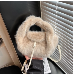 Detail einer beigen Webpelz-Handtasche mit abnehmbarem Schultergurt und Metallschnalle
