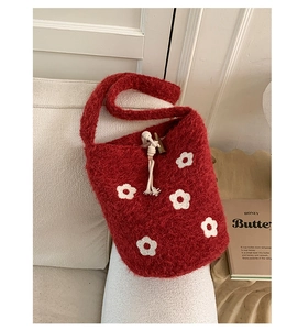 Détail du sac seau en tricot rouge avec motifs fleurs et fermoir à bascule en bois