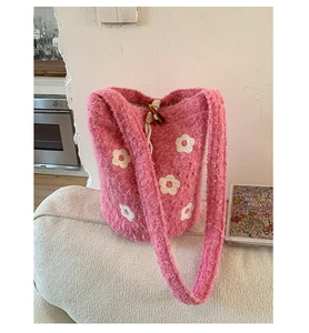 Détail du sac seau en tricot rose avec motifs floraux blancs et fermeture à cordon