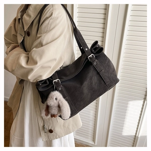 Detailed side view of a large vintage matte shoulder bag with a cute plush bunny charm