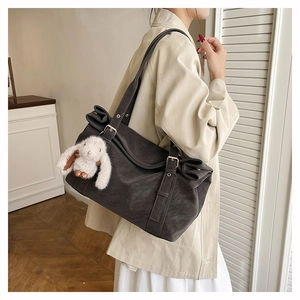 Detail of dark grey tote bag with matte texture and a cute white bunny pendant charm