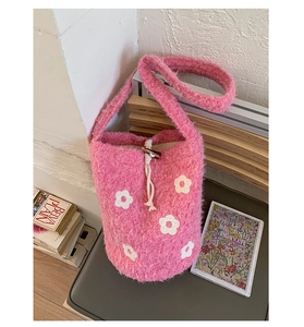 Détail du sac seau en peluche rose avec motifs de fleurs et fermeture à cordon