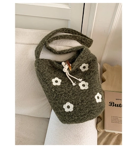 Détail du sac seau en maille verte avec fleurs au crochet et fermeture boucle corne