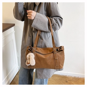 Brown large shoulder bag with cute white bunny pendant and adjustable strap on a model