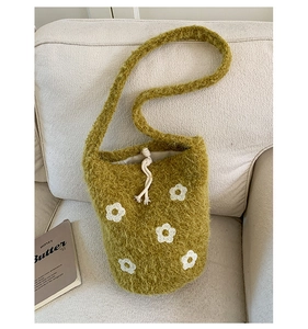 Détail du sac seau en peluche verte avec motifs floraux blancs et fermeture à cordon