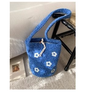 Détail du sac seau bleu en tricot avec motif floral blanc et fermeture à cordon