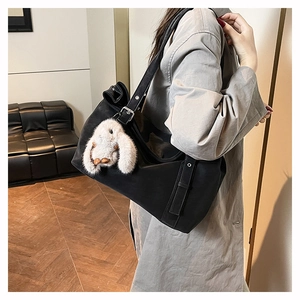 Detail of minimalist black matte shoulder bag with cute white plush bunny charm