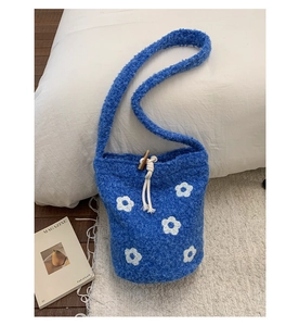 Détail du sac seau bleu en polaire teddy avec motifs de fleurs blanches et cordon de serrage