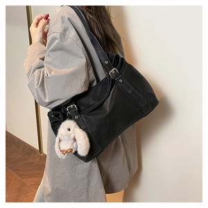 Detail of black matte tote bag with silver buckle strap and white bunny charm