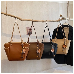 Dettaglio di grandi borse shopper in quattro colori con ciondoli floreali su un ramo