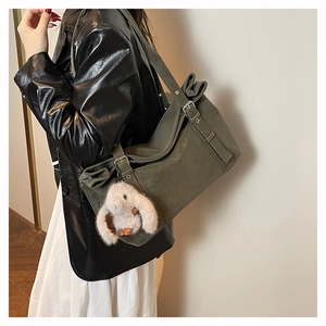 Detail of olive green matte shoulder bag with a cute white bunny pendant on the strap