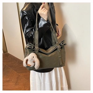Detail of large olive green matte tote bag with long handles and white plush bunny charm
