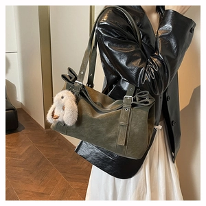 Detail of olive green tote bag with matte texture and cute white plush bunny charm