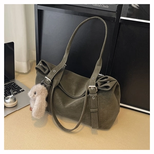 Macro view of matte olive green tote bag showing side buckle and plush bunny charm