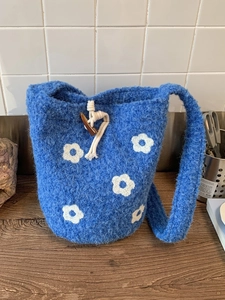 Sac seau en tricot bleu avec motifs floraux blancs et fermeture par bouton en bois