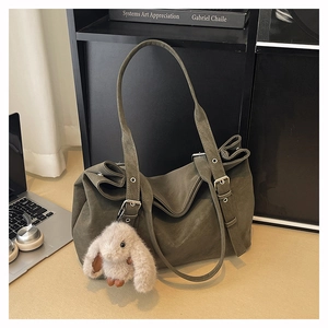 Close-up of olive green matte suede tote bag with metal buckle and cute rabbit charm