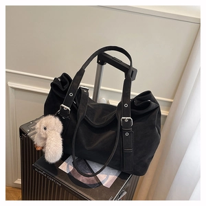 Detail of matte black leather tote bag with silver buckle and plush bunny charm