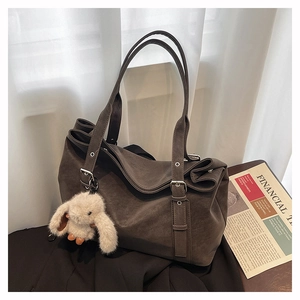Detail of dark brown matte leather tote bag with silver buckle and plush bunny charm
