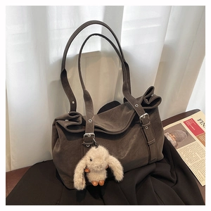 Detail view of large dark brown tote bag with matte texture and cute plush bunny charm