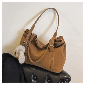 Detail of brown vintage leather tote bag with silver buckle and white rabbit pendant