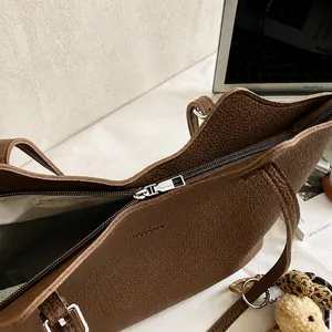 Close-up of brown litchi pattern leather tote bag showing silver metal zipper and logo