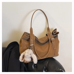 Detail of brown matte leather tote bag with metallic eyelets and white plush bunny charm