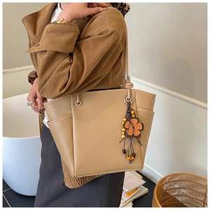 Dettaglio della borsa tote in pelle color cammello con ciondolo a fiori e perline