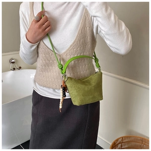 Detalle de bolso saco de ante verde con colgante étnico de cuentas llevado por modelo