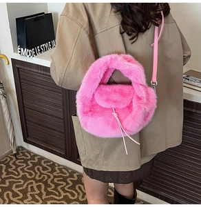 Detail einer leuchtend rosa Plüschhandtasche mit Riemen auf einem khakifarbenen Mantel
